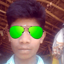 a boy wearing a pair of green sunglasses looks at the camera