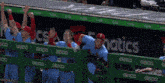 a group of baseball players standing behind a green fence that says geico on it