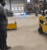 a man stands in front of a yellow cat forklift in a warehouse