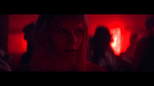 a blurry picture of a woman in a dark room with red lights behind her