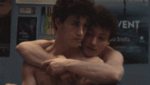 a couple of men hugging in front of a poster that says vent