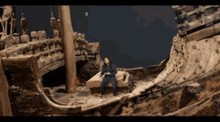 a man sits on a rock in front of a destroyed ship