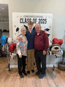 a group of people standing in front of a congratulations class of 2025 sign