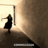 a woman in a black dress is running down a hallway with the words coming gg gg written on the bottom
