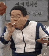 a man is smoking a cigarette in front of a sign with korean writing on it .