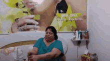 a woman is sitting in a chair in front of a picture of a woman holding a glass of water .
