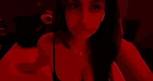 a woman is sitting on a bed in a dark room in a red light .