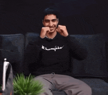 a man sitting on a couch wearing a champion sweatshirt