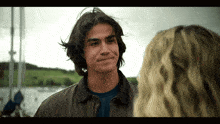 a man with long hair looks at a woman