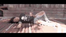 a man wearing a t-shirt with a skull and crossbones on it is laying on a roof