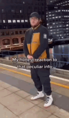 a man is standing on a sidewalk in front of a building and talking about his honest reaction to that peculiar info .