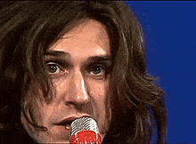 a close up of a man singing into a microphone