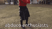 a man in a kilt is standing in a grassy field with the words abduco enthusiasts on the bottom