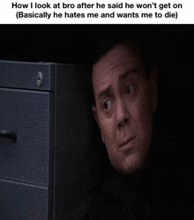 a man is peeking out from behind a filing cabinet