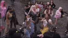 a group of women are standing on a street and one of them is wearing a pink hooded jacket