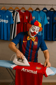 a clown is ironing an arsenal shirt on a ironing board