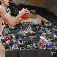 a basketball player is holding a basketball in front of a crowd and a sign that says quest
