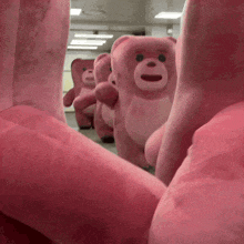 a row of pink teddy bears are standing in a room