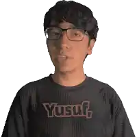 a man wearing glasses and a black shirt with the word yusuf on it