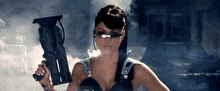 a woman in a futuristic outfit is holding a gun in her hand