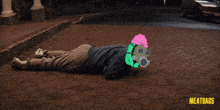 a man wearing a gas mask is laying on the ground in front of a car with meatbags written on the bottom