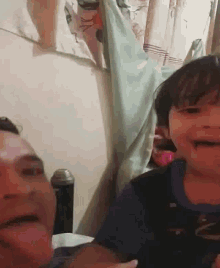 a man and a child are making funny faces in a bedroom .