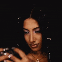 a woman with a nose ring looks at herself in a mirror