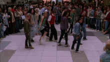 a crowd of people are gathered on a tiled floor in front of a sign that says ' a ' on it