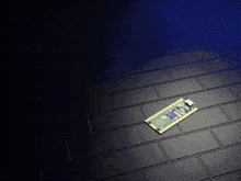 a small electronic board is laying on a black tile floor
