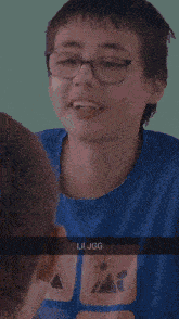 a boy wearing glasses and a blue shirt that says lil jgg on it
