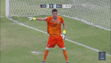 a soccer player in orange stands in front of a goal with the score of 0-1