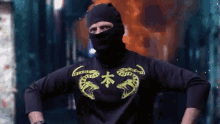 a man wearing a black mask and a black shirt with yellow dragons on it