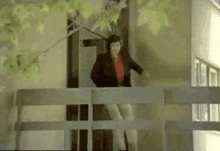 a woman in a red shirt is standing on a balcony looking out a window