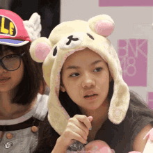 a girl wearing a hat that looks like a teddy bear with the number 18 behind her