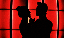 a man and a woman are dancing in front of a red background