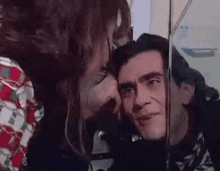 a woman is kissing a man on the cheek in a mirror .