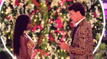 a man and woman are standing next to each other in front of a heart shaped flower arrangement .