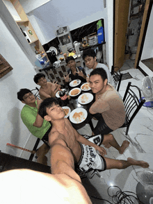 a group of young men are sitting around a table with plates of food and a coca cola bottle
