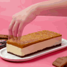 a person reaches for a snickers bar on a white plate