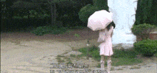 a young girl in a pink dress is holding an umbrella in front of a statue .