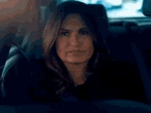 a woman is sitting in the back seat of a car and making a face .