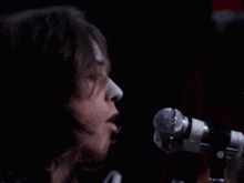 a woman singing into a microphone with a hand on her face