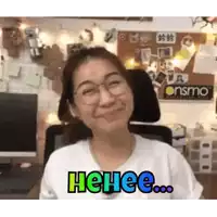 a woman wearing glasses and a white shirt is smiling while sitting in a chair .