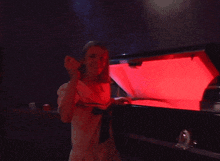 a woman in a white shirt is standing in front of a red light