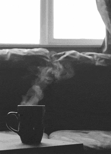 a black and white photo of a cup of steaming coffee