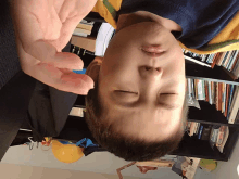 a young boy with his eyes closed is laying on his back in front of a bookshelf
