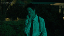 a man in a white shirt and black tie is smoking a cigarette in the dark with the words terasgifs above him