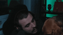 a man wearing headphones is being attacked by a dog who is looking at his face
