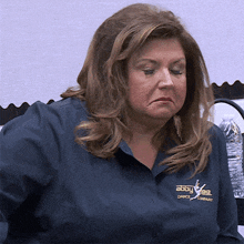 a woman wearing a blue shirt with abby lee dance company written on it