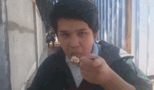 a young boy is eating a piece of food with a spoon in his mouth and the word vidu is on the bottom right